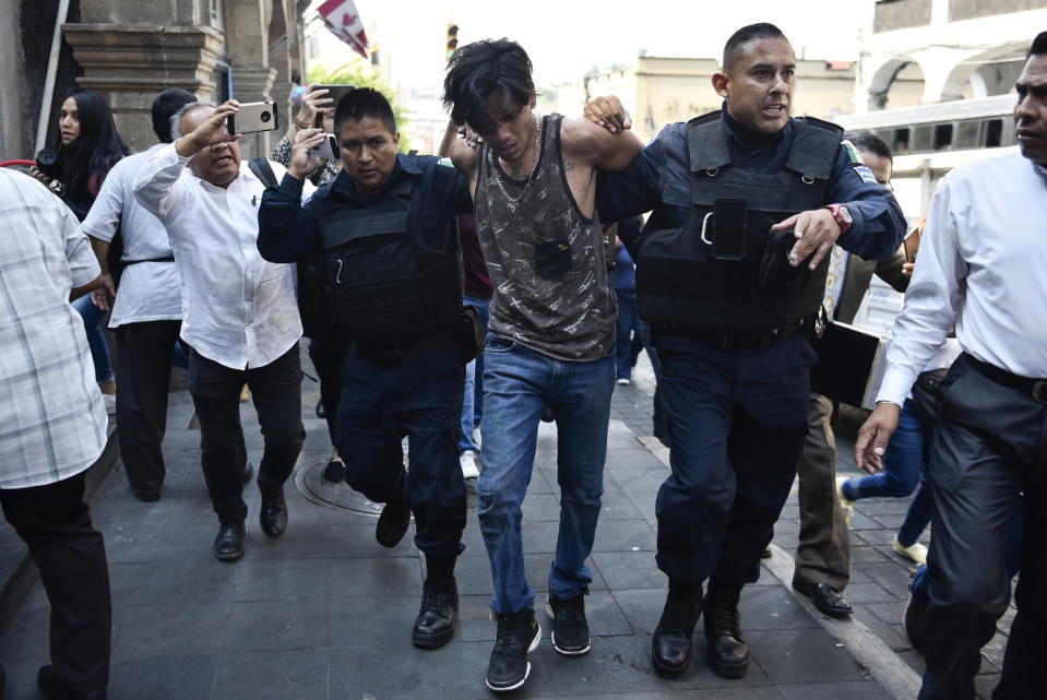 Police arrest a man who started shooting outside City Hall in Cuernavaca, Mexico, Wednesday, May 8, 2019. The man opened fire at the entrance of City Hall where journalists were interviewing government officials, killing two people, including a union member who was apparently with street vendors who were protesting nearby, and injuring two others, according to officials. (AP Photo/Tony Rivera)