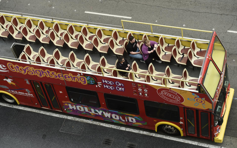 Passengers sit in a mostly empty sightseeing bus on Hollywood Boulevard, Thursday, March 12, 2020, in the Hollywood section of Los Angeles. (AP Photo/Chris Pizzello)