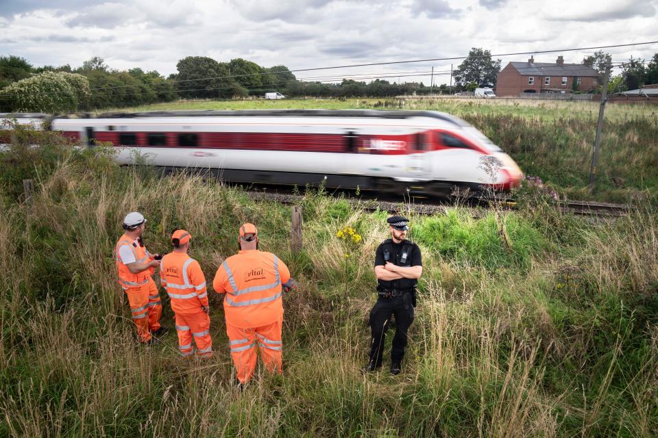 Police and railway workers near the scene in Balderton, near Newark-on-Trent. A police officer is in a serious condition after being hit by a train while trying to save a distressed man who was on the tracks. Nottinghamshire Police said officers were deployed to a residential area in Balderton just before 7pm on Thursday, over concerns for a man's safety. Picture date: Friday August 25, 2023.