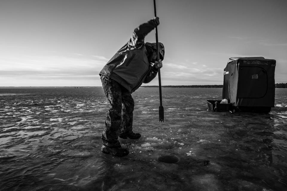 Trey Pipesh punches a hole in the ice on Tawas Bay on Lake Huron on Dec. 22, 2019. An auger is normally required to drill through thick ice, but on this day the ice is thin enough to pierce through with a spud -- a long piece of steel that is tapered at the end and usually used to test or measure the thickness of the ice. (Photo: Amy Sacka for HuffPost)