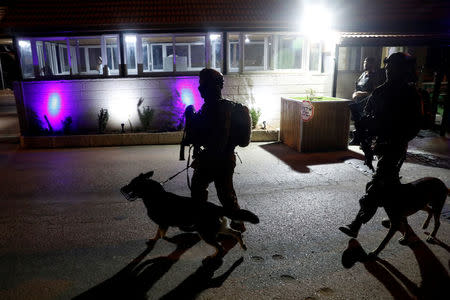 Israeli soldiers patrol with their dogs near the entrance of Israeli settlement Adam after a Palestinian assailant stabbed three people and then was shot and killed, according to the Israeli military, in the occupied West Bank, July 26, 2018 REUTERS/Ronen Zvulun