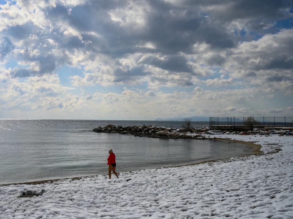 A swimmer walks on a snow covered beach after a heavy snowfall in Athens (AFP via Getty Images)