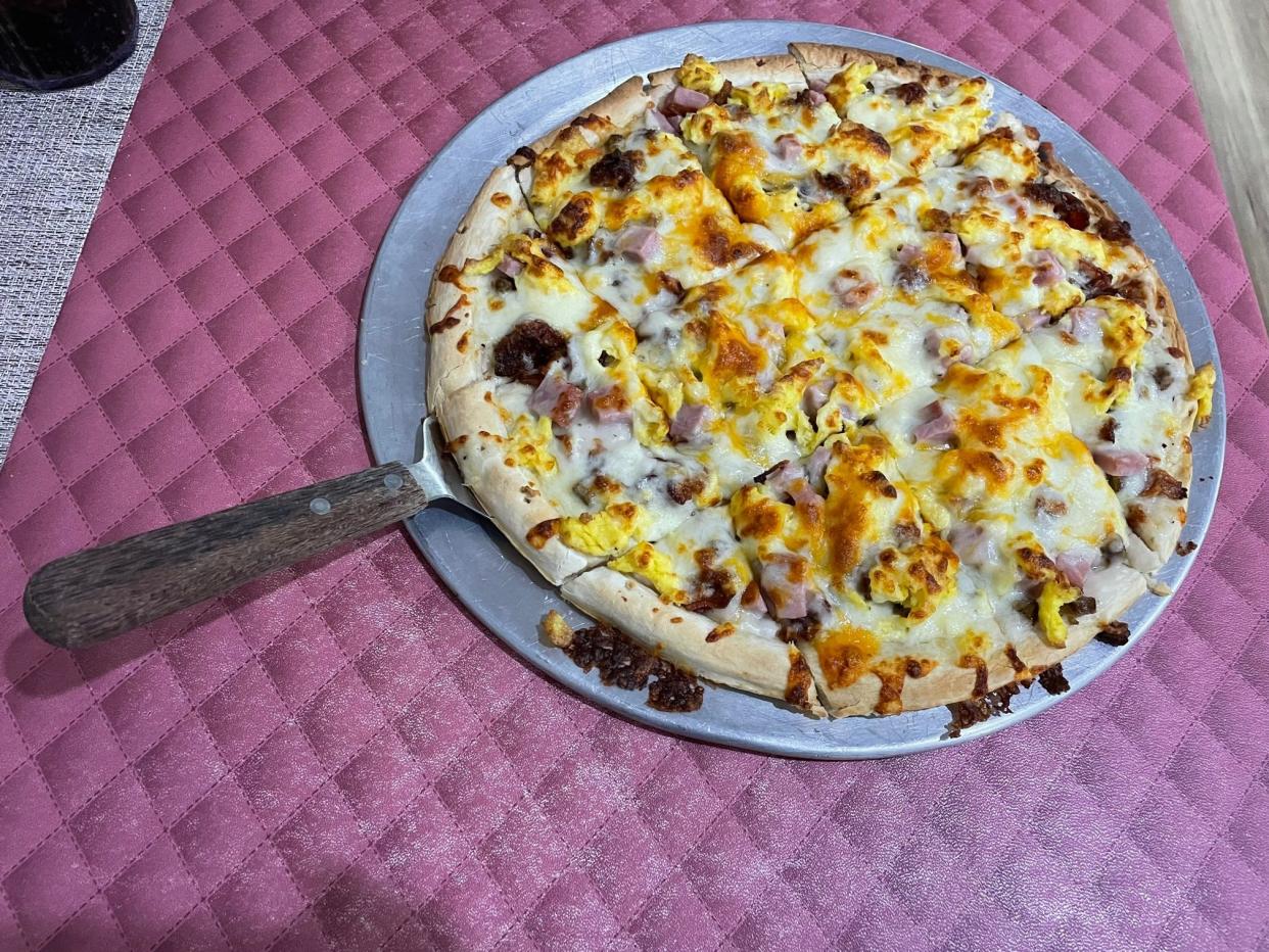 The Lighthouse Meat Lovers Breakfast Pizza is a 12” pizza topped with ham, bacon, sausage, scrambled eggs, biscuit gravy and shredded mozzarella.