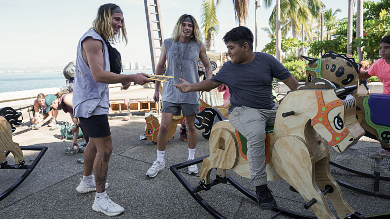  Twins Bailey Smith and Anthony Smith pass a note to a boy on a rocking horse in "The Amazing Race" season 36. 