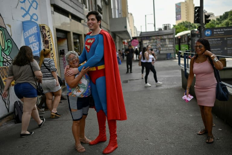 Leonardo Muylaert, le "Superman brésilien", avec une habitante du quartier de Tijuca, le 18 mars 2024 à Rio de Janeiro (MAURO PIMENTEL)