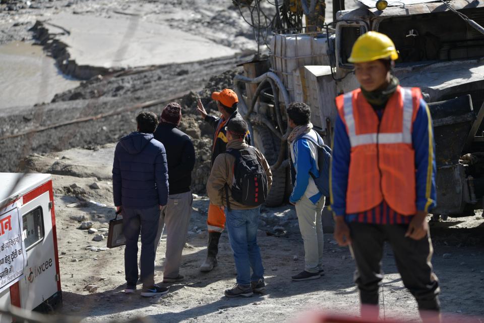 Defence research and development organisation (DRDO) scientists talk with an emergency and rescue official (in orange cap) after arriving near Tapovan tunnel, where dozens are still feared to be trapped, during rescue operations in Tapovan of Chamoli district on February 12, 2021 following a flash flood thought to have been caused when a glacier burst on February 7. (Photo by Virender SINGH NEGI / AFP) (Photo by VIRENDER SINGH NEGI/AFP via Getty Images)