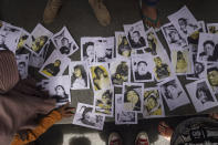 People looking for their relatives inspect photographs of soccer riot victims provided by volunteers to help them identify their family members in Malang, East Java, Indonesia, Sunday, Oct. 2, 2022. Panic at an Indonesian soccer match Saturday left over 150 people dead, most of whom were trampled to death after police fired tear gas to dispel the riots. (AP Photo/Dicky Bisinglasi)