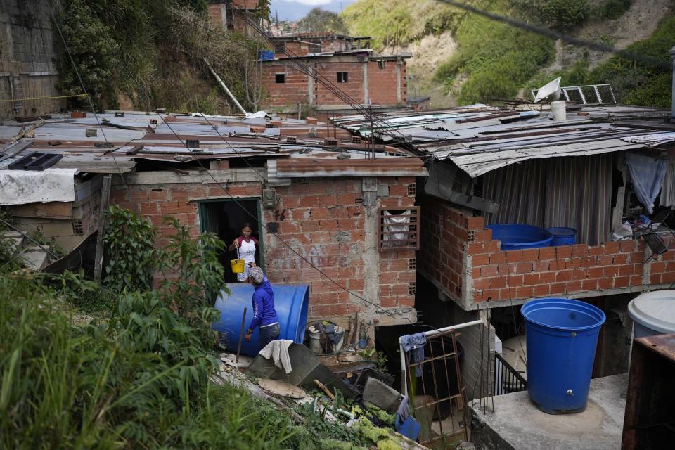 Franklin Caceres talks with Banesky Fuentes ashe to fills her container with water pumped from a well in the Petare neighborhood of Caracas, Venezuela, Monday, March 20, 2023. Caceres supplies water to more than 400 people in the upper sector of Petare as the celebration of World Water Day on March 22 is set to coincide with the start of the UN 2023 Water Conference in New York, aimed at solving the water and sanitation crisis. (AP Photo/Matias Delacroix)