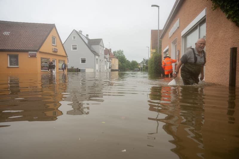 A man drags sandbags along a flooded street. After the heavy rainfall of the last few days, there was severe flooding in the region. Stefan Puchner/dpa