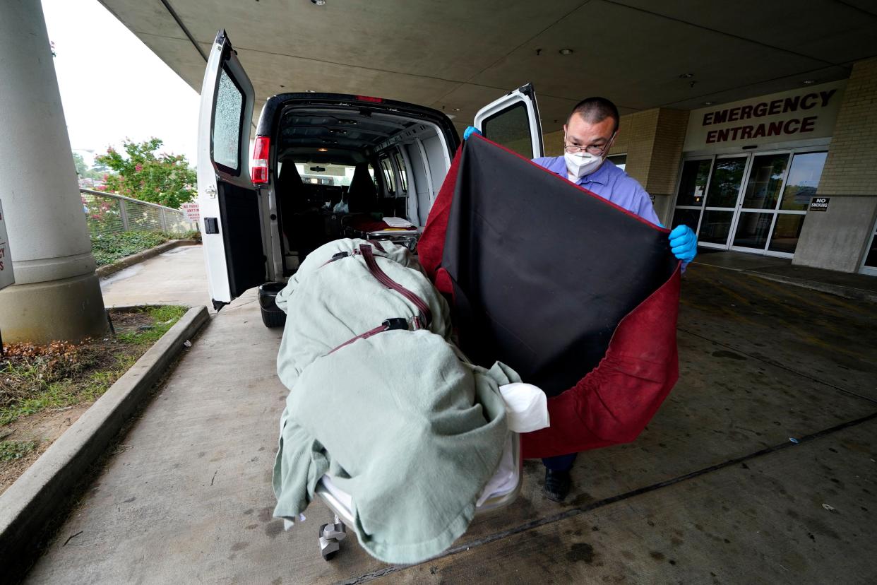 In this Aug. 18, 2021, file photo, an employee of a local funeral home covers the body of a COVID-19 patient patient who died as he prepares to take it away from a loading dock, at the Willis-Knighton Medical Center in Shreveport, La.