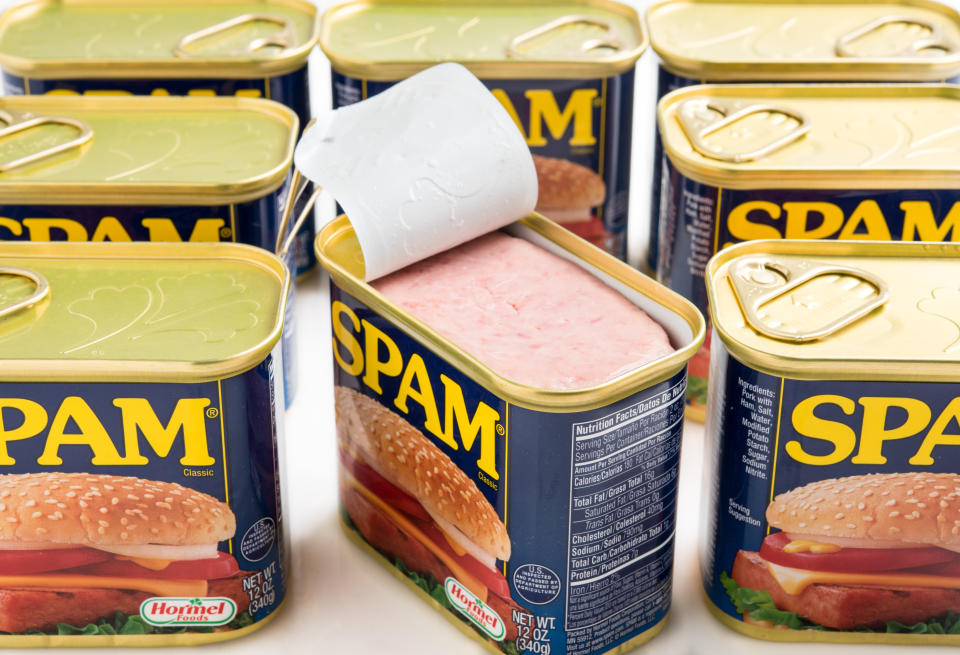 Eight Spam canned meat containers, the middle one open, showing off the popular meat on a white background. (Photo via Getty Images)