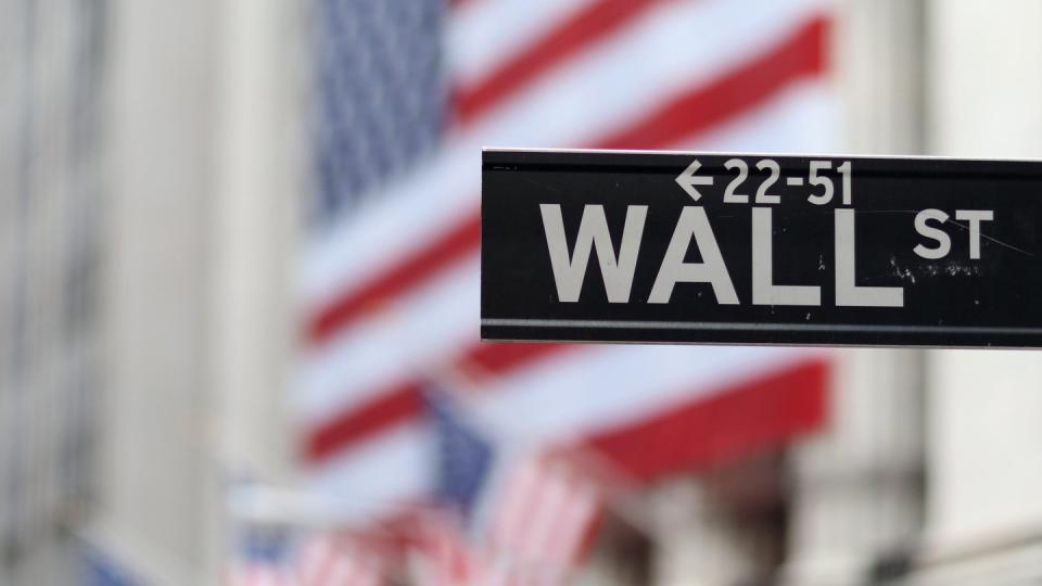 Blick auf die Börse in New York hinter dem Straßenschild der Wall Street. Foto: Andrew Gombert/EPA