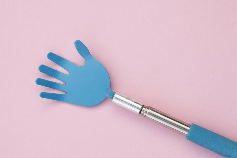 A hand-shaped back scratcher on a plain background