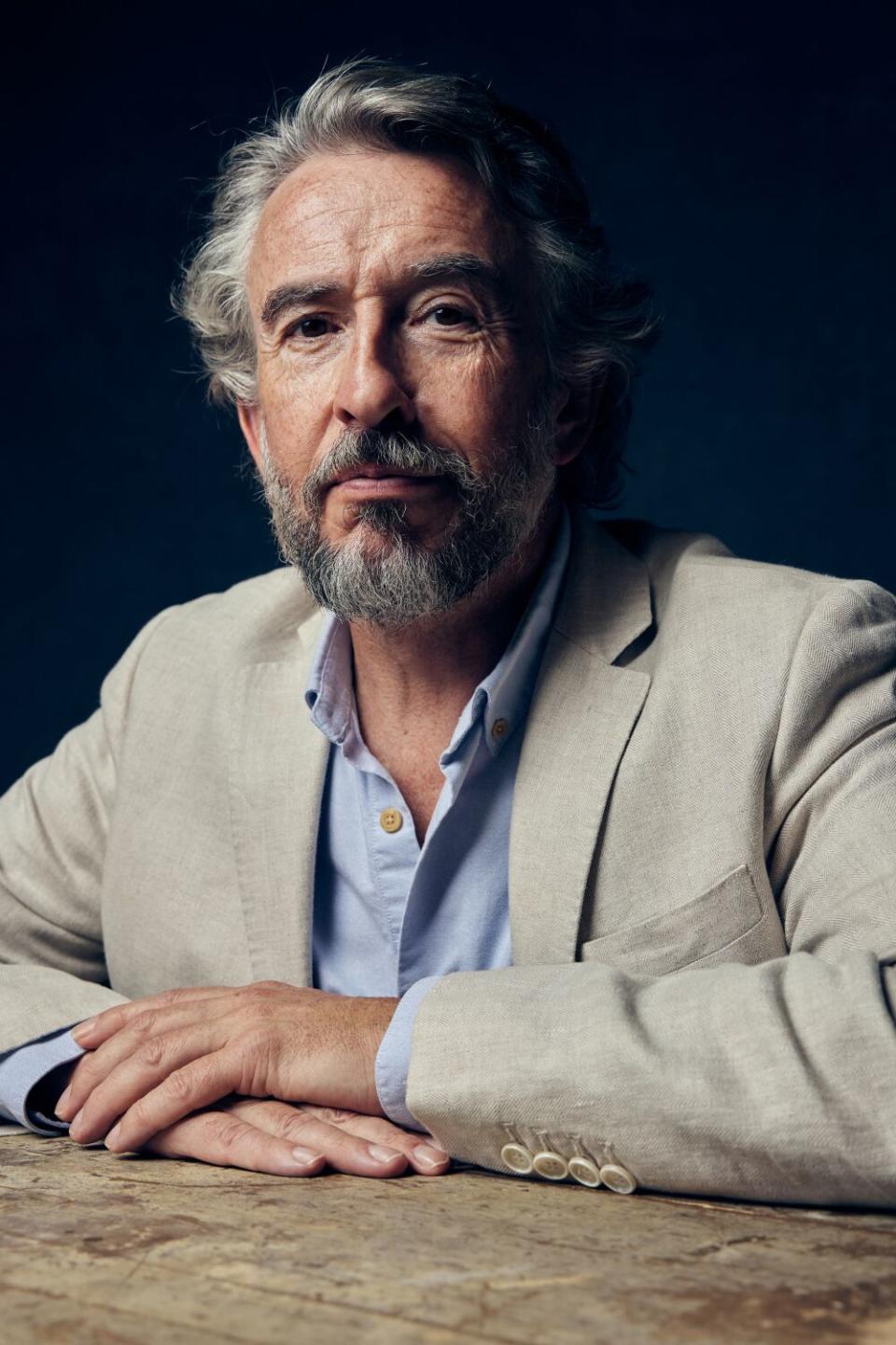 A man with his hands resting on a table.