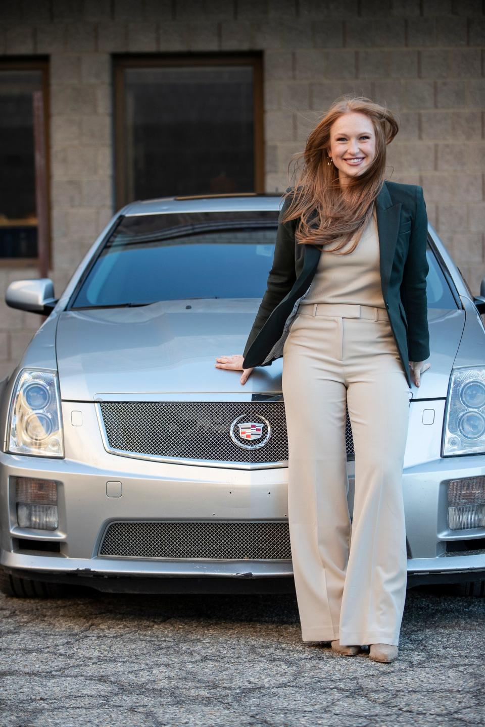 Jenna Holt, Chevrolet assistant retail planning manager, in front of her 2007 Cadillac CTS at Dress for Success in Ypsilanti on Tuesday, Dec. 12, 2023.