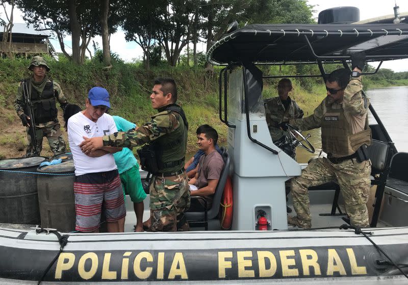 Peruvian anti-narcotics police officers and Brazilian Federal Police officers check suspects during an operation at Amazon river in Caballococha