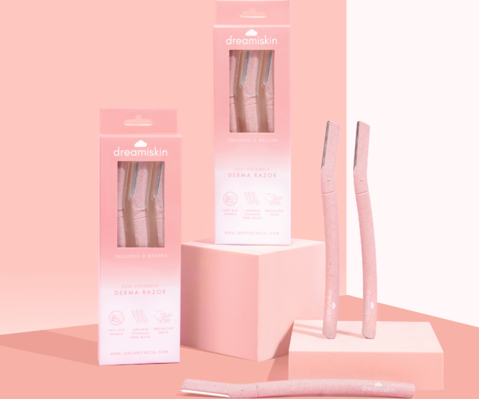 Dreamiskin's derma razors sit in their pale pink and white packs against a pale pink background.