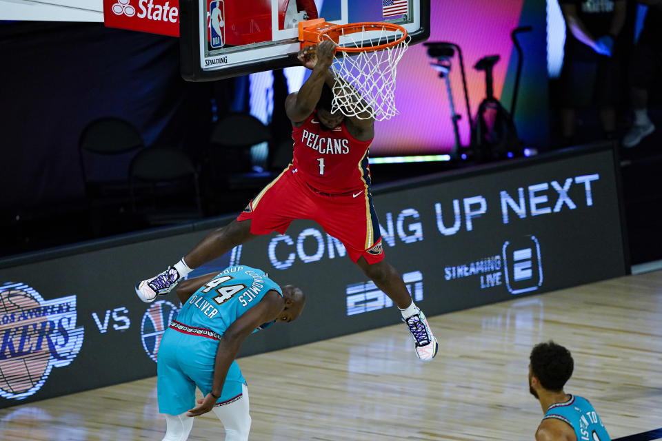 Zion Williamson hangs on the rims after throwing down a dunk.