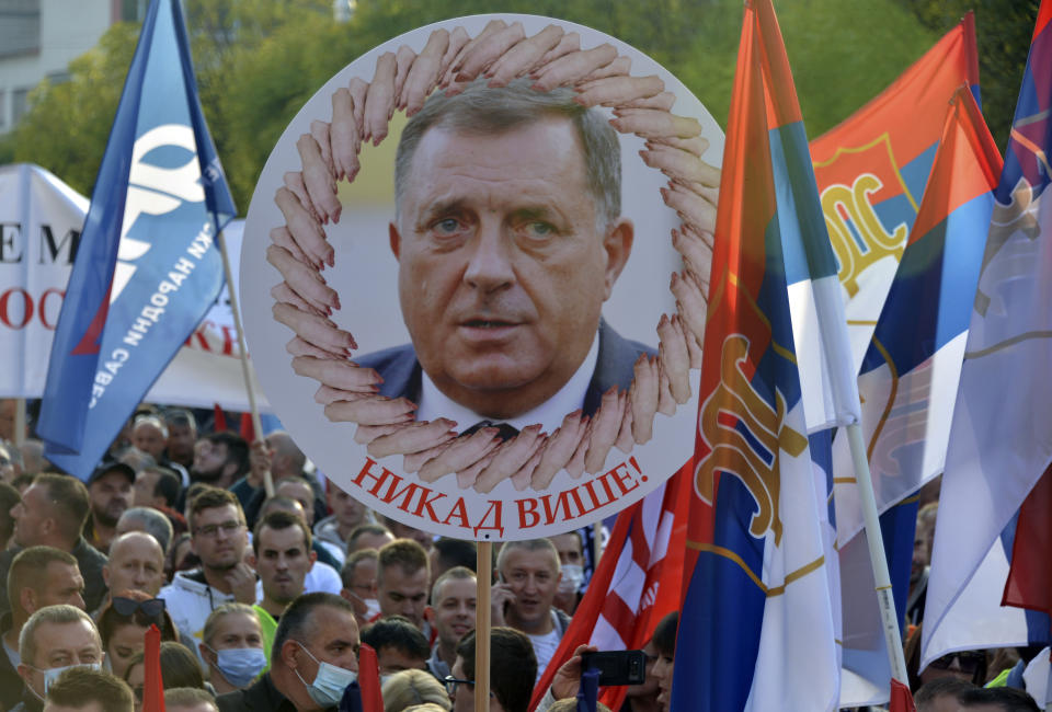 A person holds a banner showing the Bosnian Serb member of the tripartite Presidency of Bosnia Milorad Dodik that reads: "Never Again!", during a protest against the government in Banja Luka, in Serb-dominated part of Bosnia, Saturday, Oct. 2, 2021. Several thousand people have rallied against the government in Serb-dominated part of Bosnia. The protesters on Saturday accused the ruling party of nationalist leader Milorad Dodik of crime and corruption and called for its ouster. (AP Photo/Radivoje Pavicic)