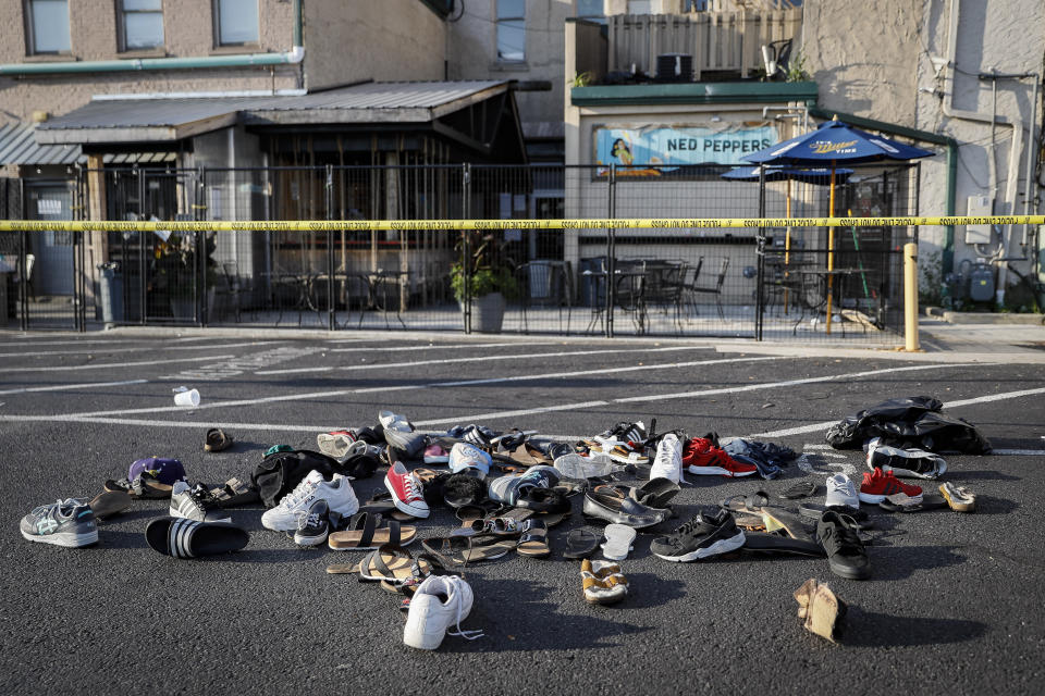 Shoes are piled outside the scene of a mass shooting including Ned Peppers bar, Sunday, Aug. 4, 2019, in Dayton, Ohio. Several people in Ohio have been killed in the second mass shooting in the U.S. in less than 24 hours, and the suspected shooter is also deceased, police said. (AP Photo/John Minchillo)