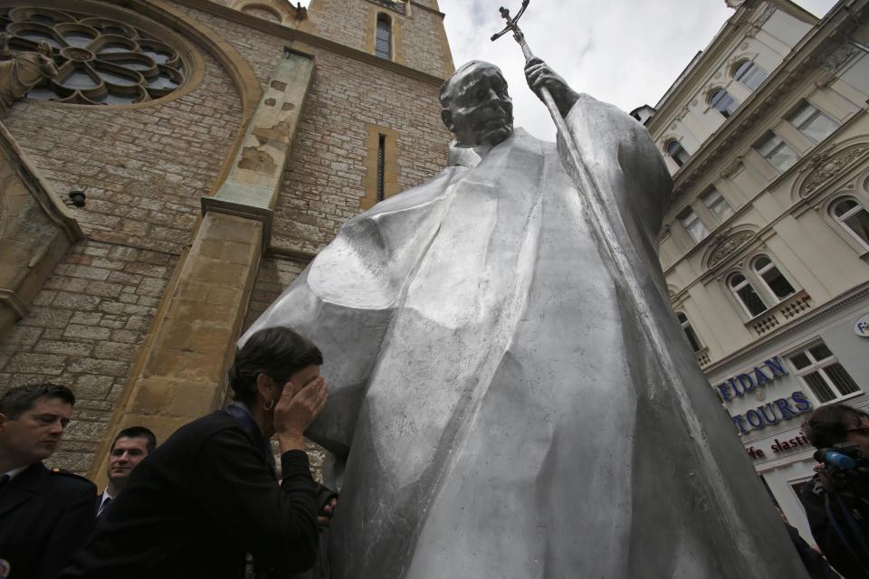 A woman touches the statue of Pope John Paul II in front of the cathedral in Sarajevo, Bosnia, on Wednesday, April 30, 2014. Thousands of Bosnians have celebrated the canonization of Pope John Paul II by unveiling a statue in the heart of Sarajevo. John Paul’s support for Sarajevo's resistance to nationalist efforts to destroy the traditional inter-cultural and inter-religious fabric of the city during the 1992-95 war made him very popular among the city's predominantly Muslim population. The crowd shouted “long live the pope” as the three meter-high statue was unveiled Wednesday in front of the cathedral. (AP Photo/Amel Emric)
