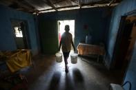 Jose Herrera carries plastic buckets with water into his house in the low-income neighbourhood of Petare amid the coronavirus disease (COVID-19) outbreak in Caracas