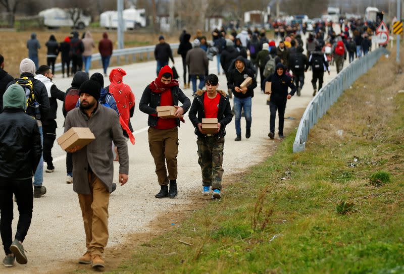 Migrants walk with boxes of food delivered by members of United Nations High Commissioner for Refugees at the Turkey's Pazarkule border crossing with Greece's Kastanies