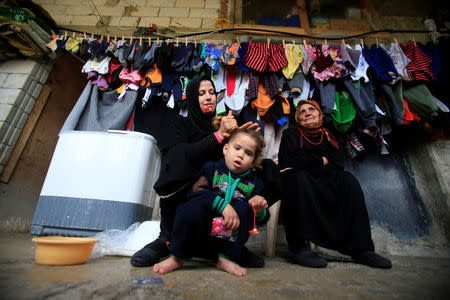 A Syrian woman fixes a girl's hair under hanged laundry at a compound housing Syrian refugees in Sidon, southern Lebanon January 25, 2017. REUTERS/Ali Hashisho