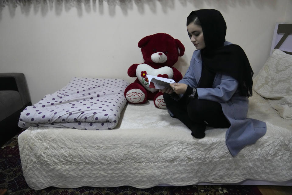 An Afghan university student Bahija Aman, 21, 3rd year anthropology major, reads a book as she sits on her bed at her home, in Kabul, Afghanistan, Thursday, Feb. 24, 2022. Kabul University, among Afghanistan’s oldest and most revered institutions of higher education, reopened Saturday six months after the Taliban retook the country. There were new restrictions in place, however, including gender segregation and mandatory Islamic dress. (AP Photo/Hussein Malla)