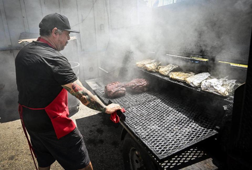 Bernard Mendoza checks on ribs and pork roasts cooking on the smoker outside BenSmokin BBQ in Fresno on Wednesday, July 12, 2023.