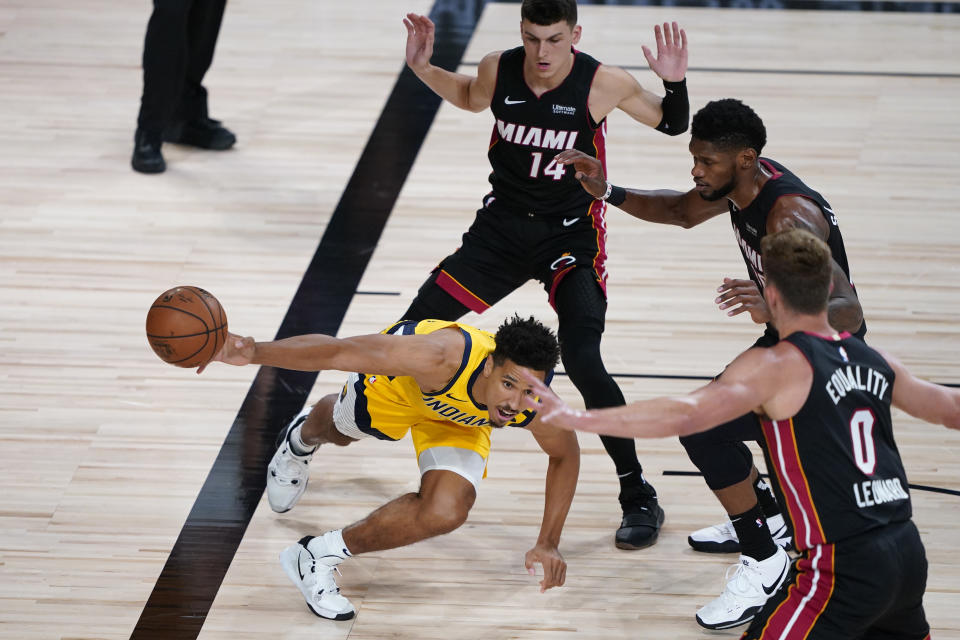 Indiana Pacers' Malcolm Brogdon tries to pass under pressure from Miami Heat's Meyers Leonard (0), Tyler Herro (14) and Chris Silva during the first half of an NBA basketball game Monday, Aug. 3, 2020, in Lake Buena Vista, Fla. (AP Photo/Ashley Landis, Pool)