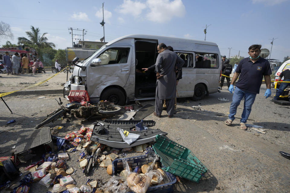 CORRECTS DATE - Pakistani investigators examine a damaged van at the site of a suicide attack in Karachi, Pakistan, Friday, April 19, 2024. Five Japanese nationals traveling in a van narrowly escaped a suicide attack when a suicide bomber detonated his explosive-laden vest near their vehicle in Pakistan's port city of Karachi on Friday, wounding three passers-by, police said. (AP Photo/Fareed Khan)