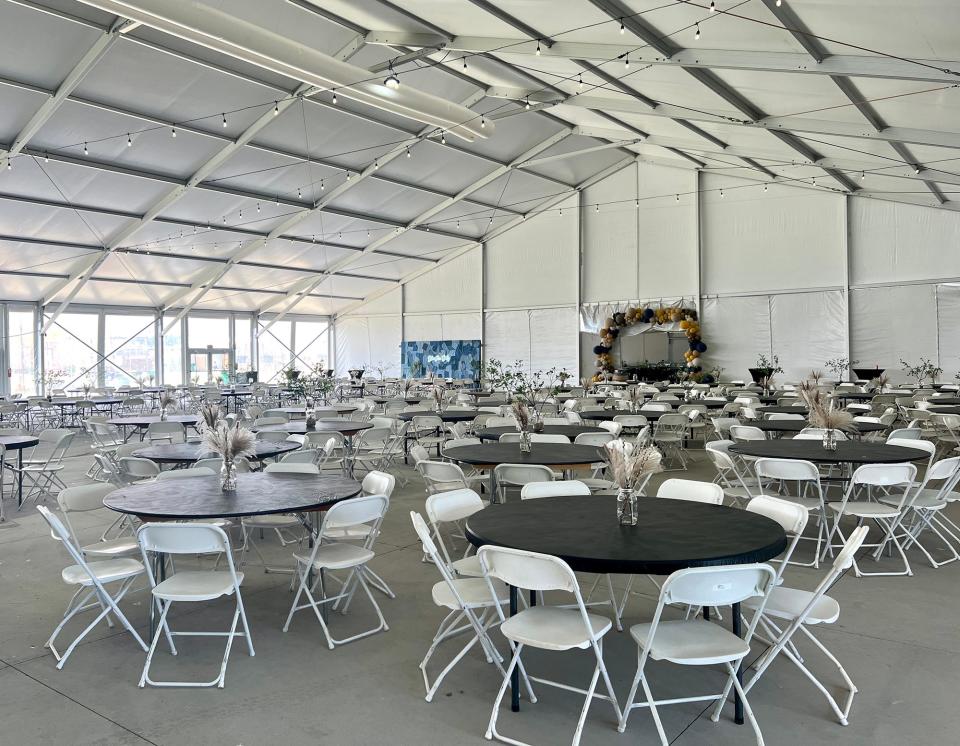 concrete slab with circle tables and white folding chairs beneath a white roof