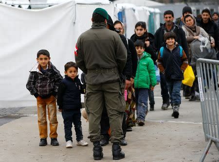 An Austrian army soldier observes migrants as they wait to cross the border from Slovenia into Spielfeld in Austria, February 16, 2016. REUTERS/Leonhard Foeger