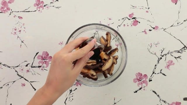 Adding oyster sauce to mushrooms in a bowl