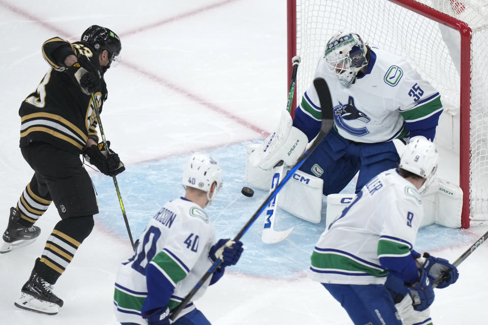 Boston Bruins left wing Brad Marchand, left, scores as Vancouver Canucks goaltender Thatcher Demko, top right, is unable to block the shot during the first period of an NHL hockey game, Thursday, Feb. 8, 2024, in Boston. (AP Photo/Steven Senne)