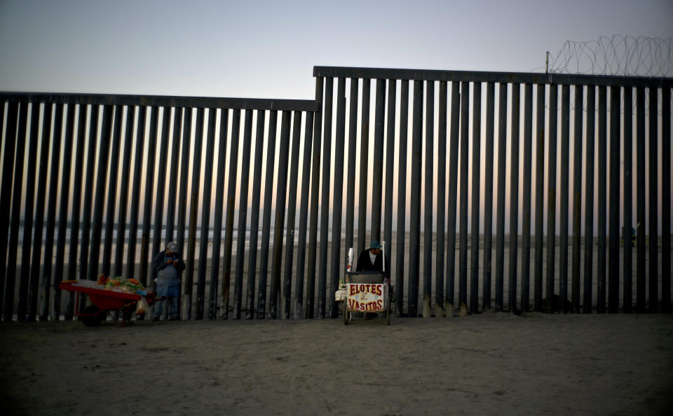 Street vendors stand at the U.S.-Mexico border structure in Tijuana, Mexico, Friday, Nov. 23, 2018. The mayor of Tijuana has declared a humanitarian crisis in his border city and says that he has asked the United Nations for aid to deal with the approximately 5,000 Central American migrants who have arrived in the city. (AP Photo/Ramon Espinosa)