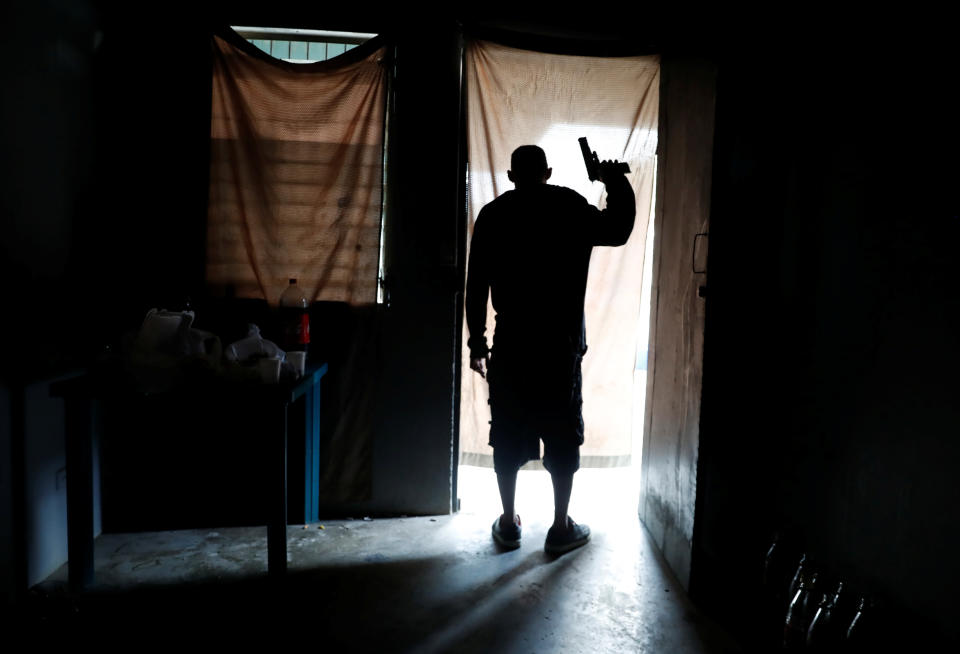 An MS-13 gang member looks out from a house as police patrol the street in San Pedro Sula, Honduras, in September. He was later injured during a gang shootout and died of his injuries, according to a police report. (Photo: Goran Tomasevic/Reuters)