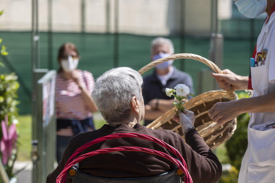 Carmela Bergamelli, 87, chooses a flower to donate to her family as she sits at a safe distance in a wheelchair at the Martino Zanchi Foundation nursing home in Alzano Lombardo, Italy, Friday, May 29, 2020. (AP Photo/Luca Bruno)