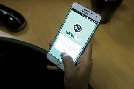 A customer uses the GrabTaxi app on her smartphone to book for a taxi in Hanoi, Vietnam September 9, 2015. REUTERS/Kham