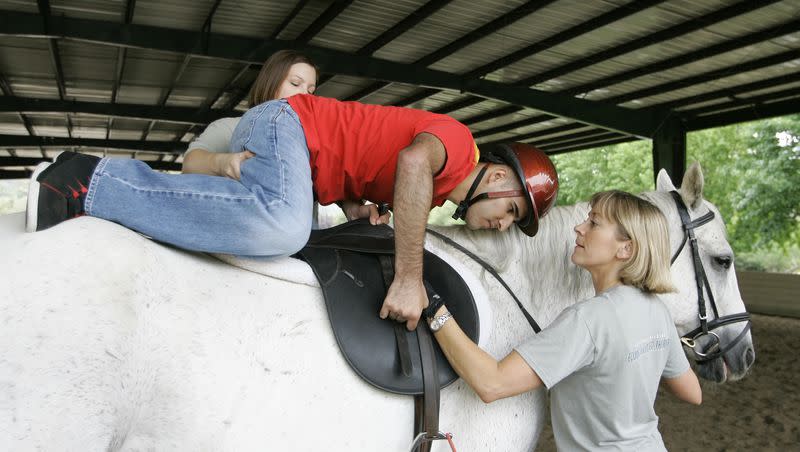 Angel Gomez gets help climbing on top of a horse during a therapy session at the National Center for Equine Facilitated Therapy in Woodside, Calif., Saturday, July 12, 2008. Equine therapy is sometimes offered by resorts and spas. 