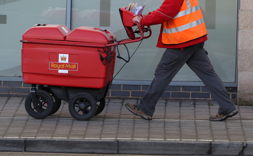 File photo dated 25/01/18 of a postman delivering letters in Woking, Surrey, as Royal Mail has said it will need to hike prices and slash costs to offset soaring inflation amid an 