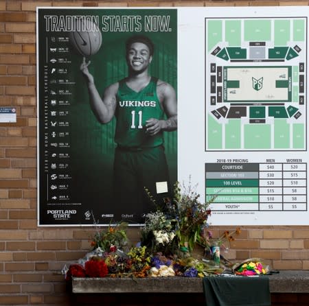 Flowers from a makeshift memorial for Deante Strickland sit beside his college basketball schedule with his photo posted outside the Peter W. Stott Center in Portland