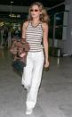 The model heads home after the Cannes Film Festival in a summery striped knit tank, white pants and square shades. 