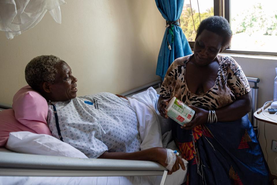 Safina Namukwaya, 70, (L) sits on a hospital bed while receiving a gift from a well wisher upon giving birth to twins at the Women's Hospital International and Fertility Centre in Kampala on December 03, 2023. Namukwaya gave birth to twins on November 29 at a medical facility in the Ugandan capital, where she had received fertility treatment.