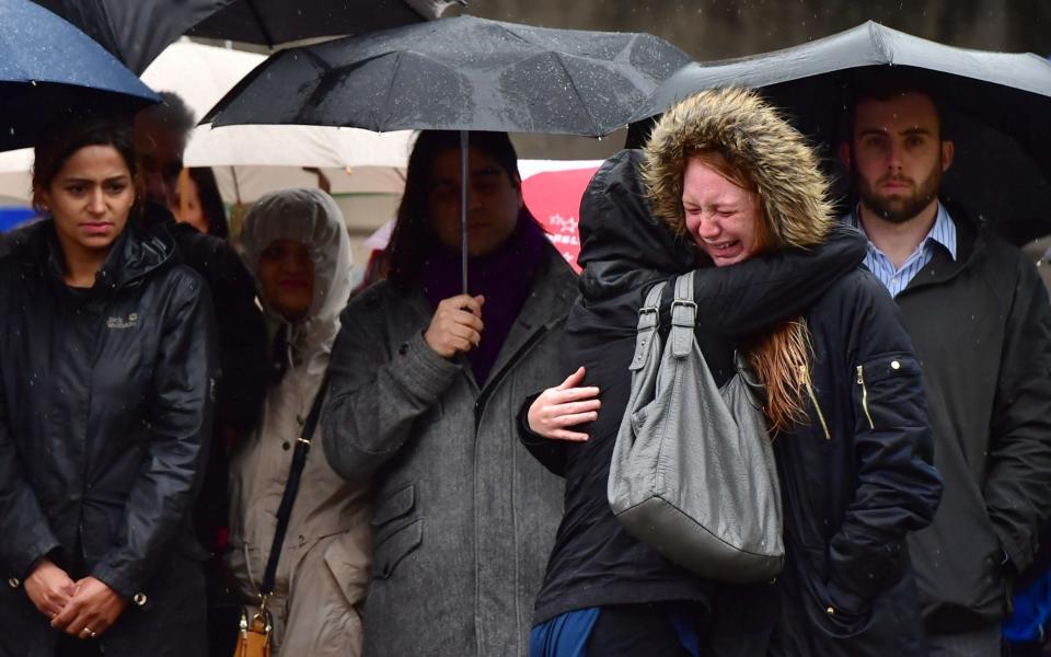 Two people become emotional while looking at the flowers left on London Bridge - Credit: Dominic Lipinski/PA Wire