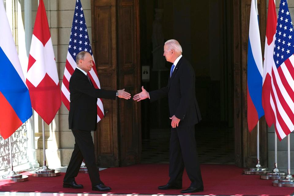 Vladimir Putin and Joe Biden preparing to shake hands.