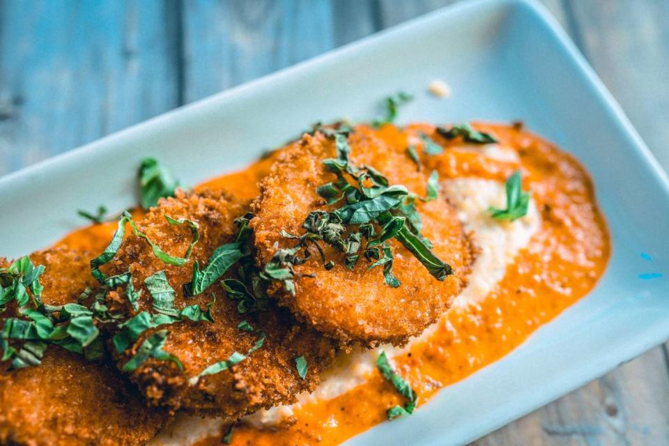 Tupelo Honey’s Famous Fried Green Tomatoes are panko-crusted and served with basil, roasted red pepper sauce on heirloom grits with goat cheese.