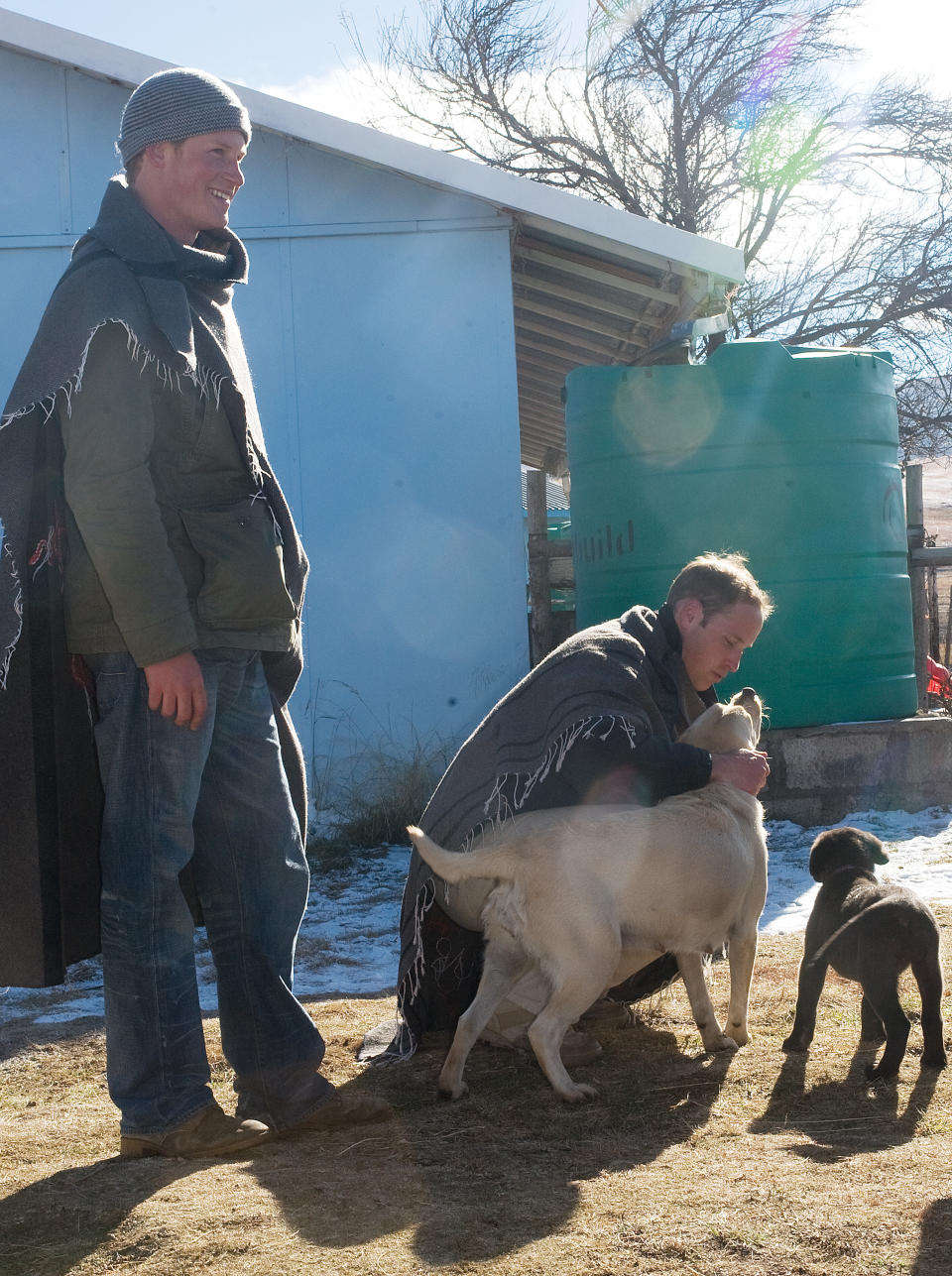 Prince William strokes a dog as he and Prince Harry visit Semongkong Children's Centre in Lesotho.