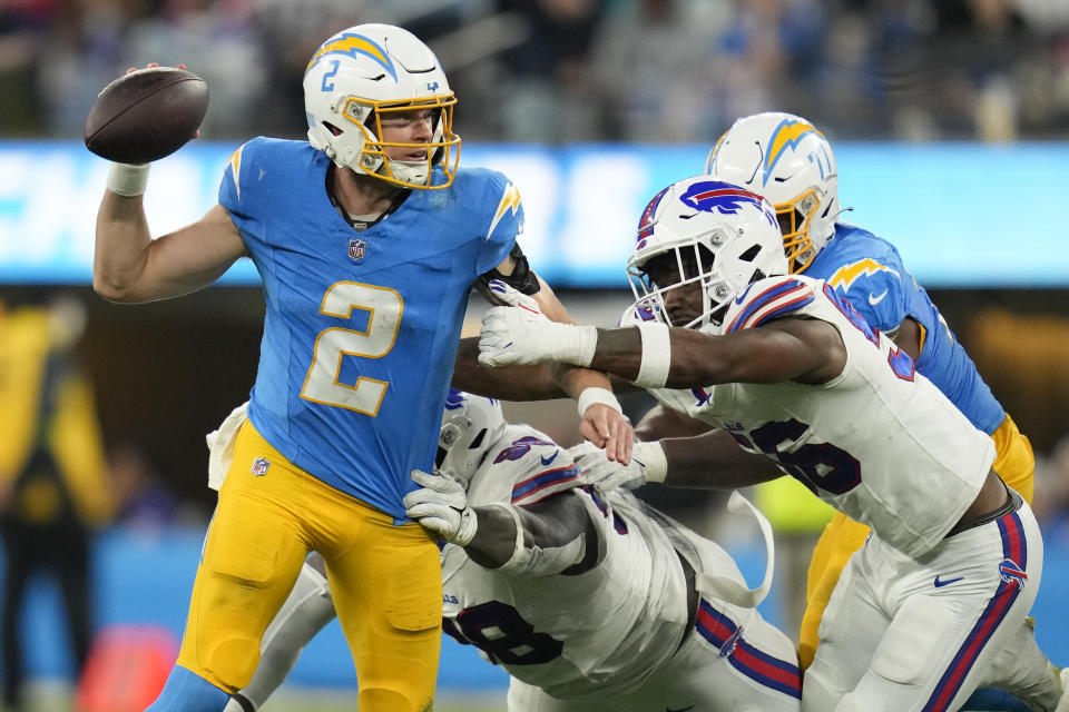 Los Angeles Chargers quarterback Easton Stick (2) is pressured by Buffalo Bills defensive tackle Poona Ford, center,, and defensive end Leonard Floyd during the second half of an NFL football game Saturday, Dec. 23, 2023, in Inglewood, Calif. (AP Photo/Ashley Landis)